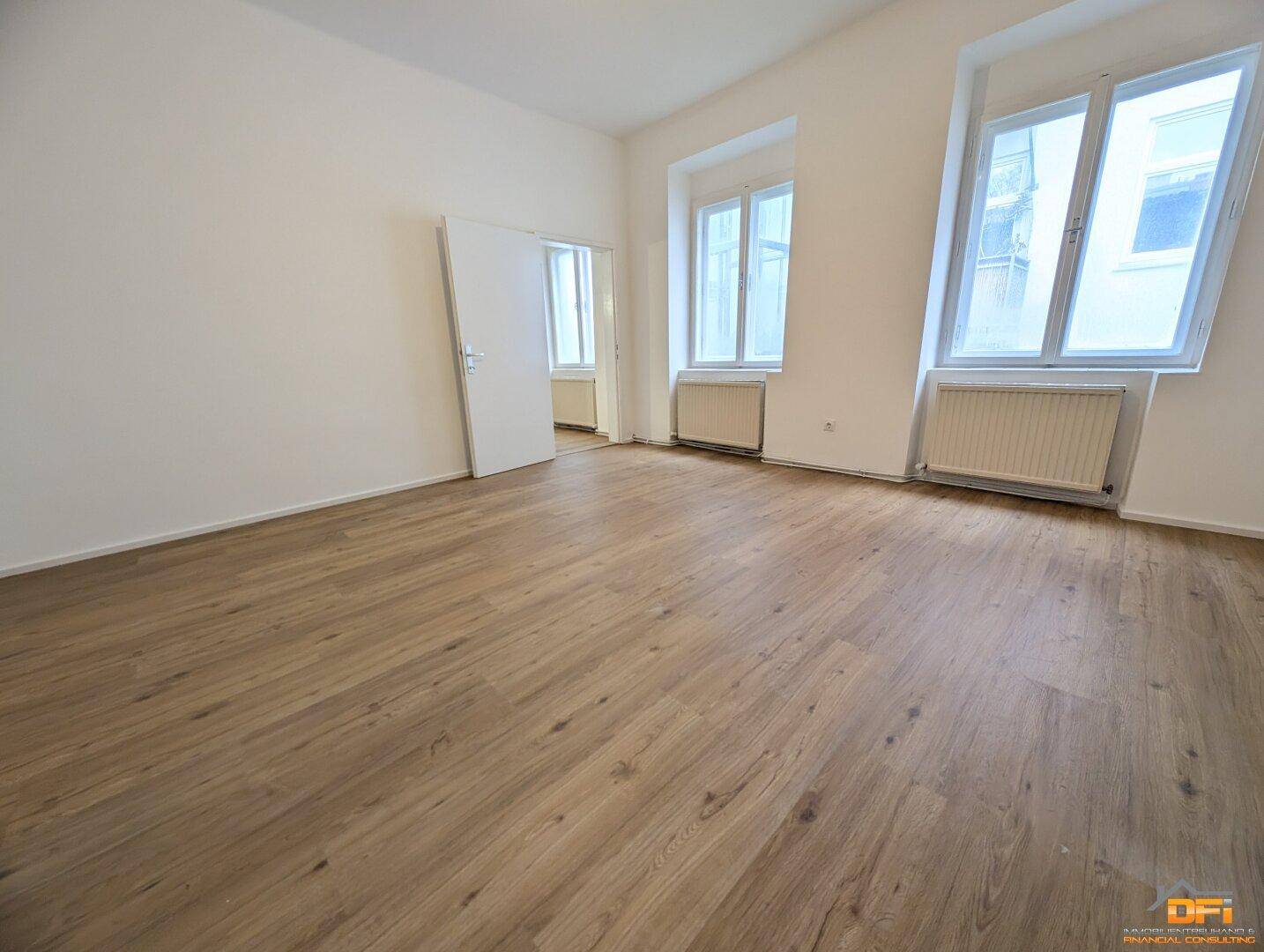 Helles Schlafzimmer mit Laminatboden, weißen Wänden und zwei Fenstern.