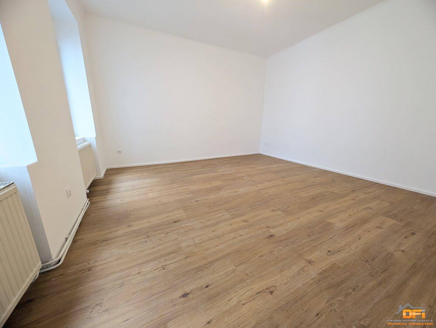 Leeres Schlafzimmer mit hellem Laminatboden und weißen Wänden, bereit zur Einrichtung.