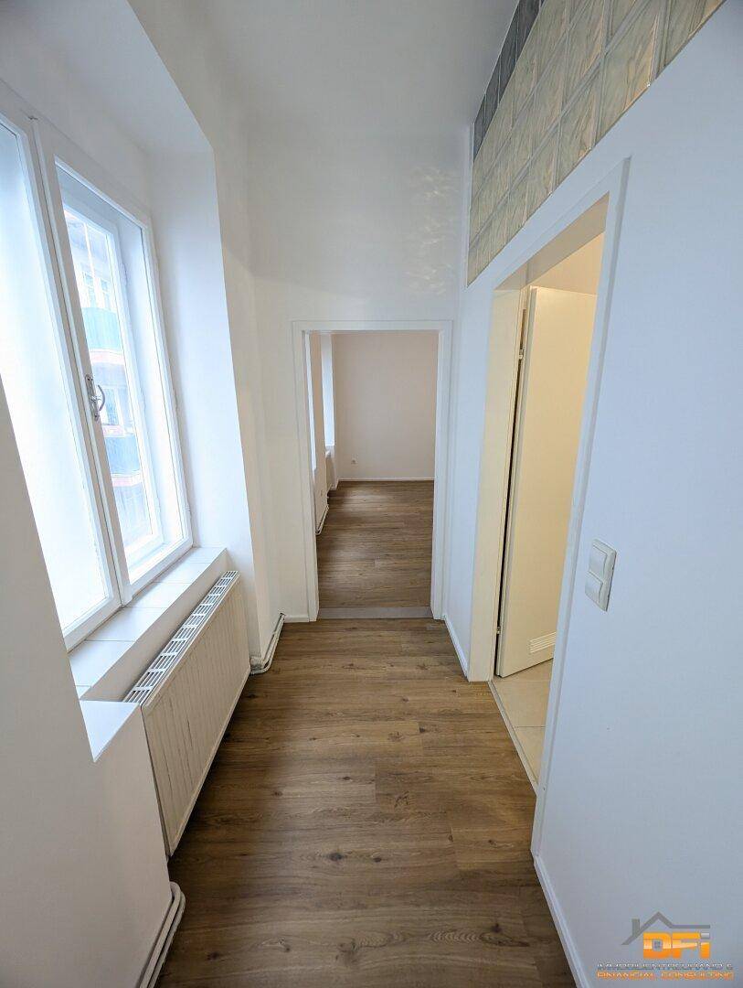 Langer, heller Flur mit Laminatboden, der zu verschiedenen Zimmern führt.