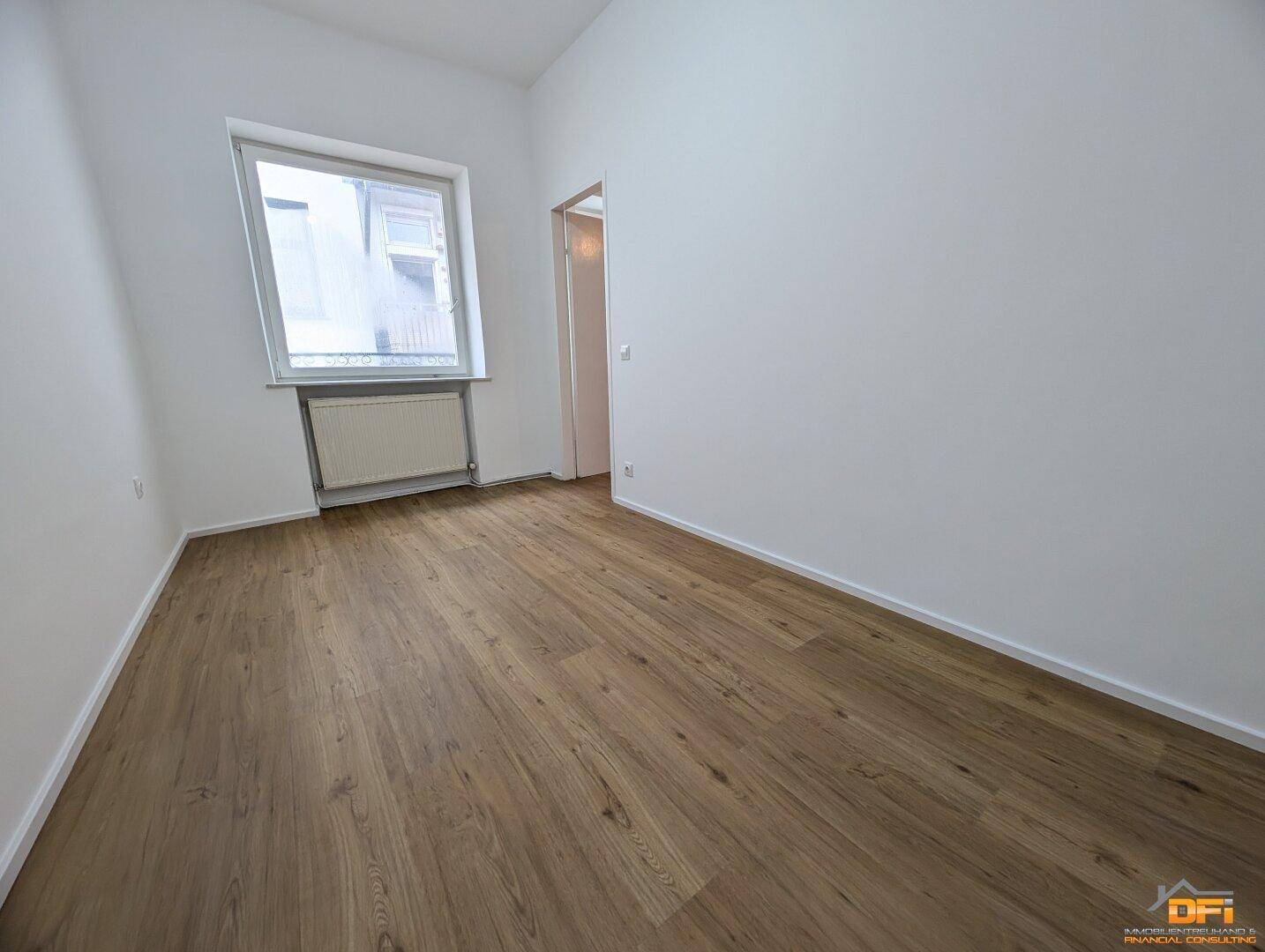 Helles Schlafzimmer mit Laminatboden und einem Fenster, ideal für Ruhe und Entspannung.