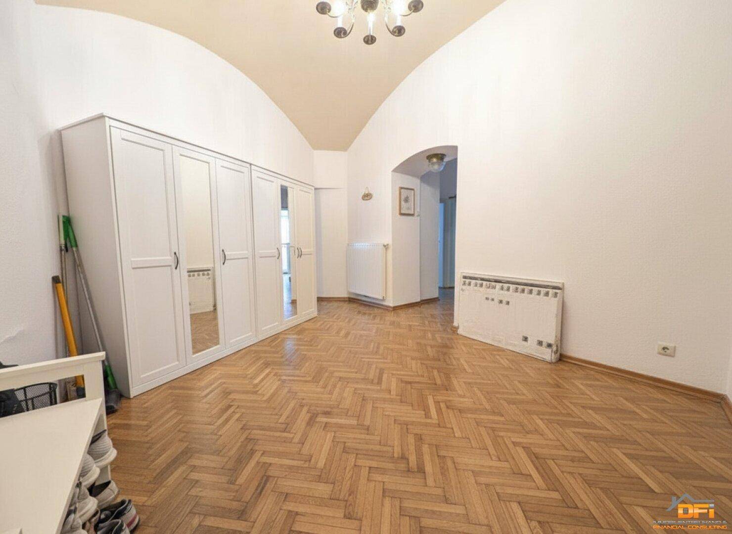 Geräumiger Flur mit Fischgrätparkett und einem großen weißen Kleiderschrank mit Spiegeltüren.