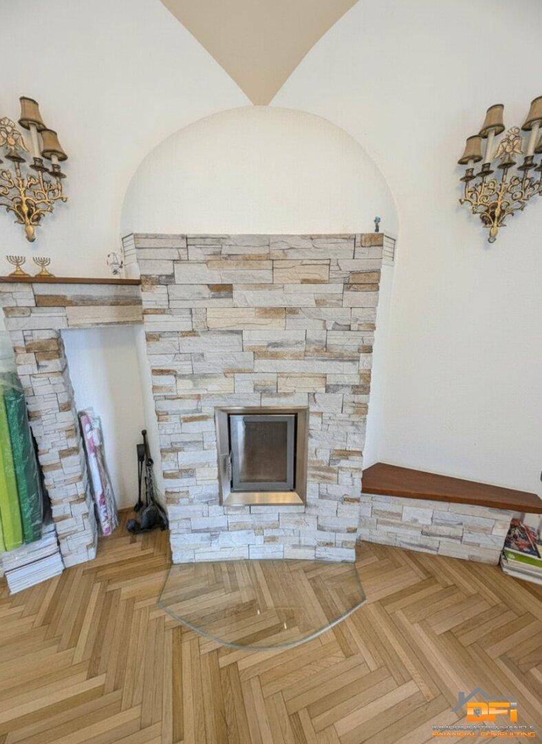 Detailansicht des steinverkleideten Kamins mit integriertem Heizeinsatz und dekorativen Wandleuchten.