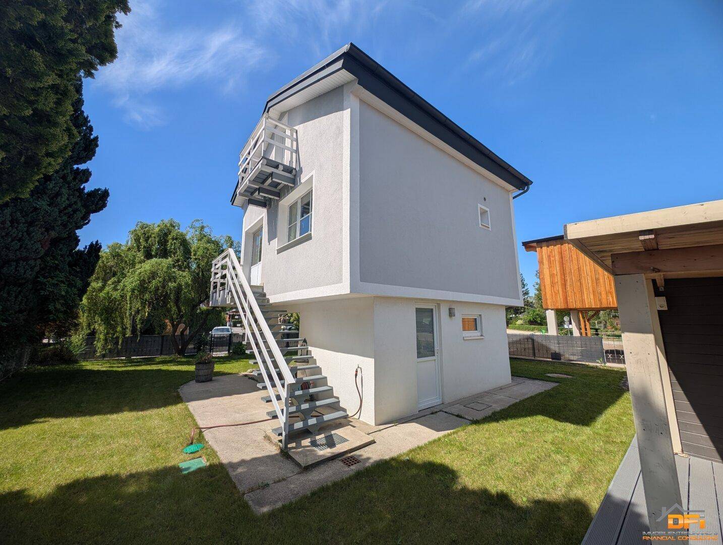 Rückansicht des modernen Hauses mit Außentreppe und gepflegtem Gartenbereich.
