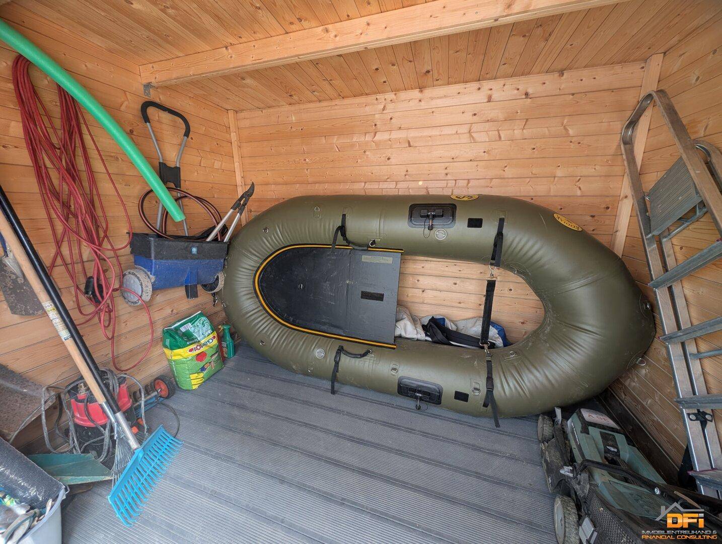 Innenansicht des Holzschuppens mit Stauraum für Gartengeräte und Schlauchboot.