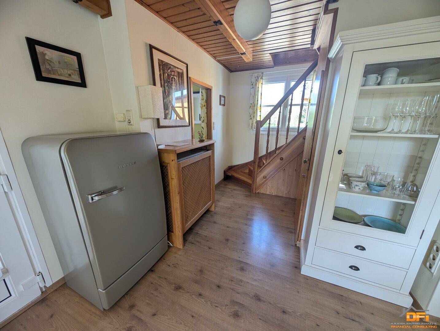 Eingangsbereich mit Holztreppe, Vitrine und Retro-Kühlschrank.