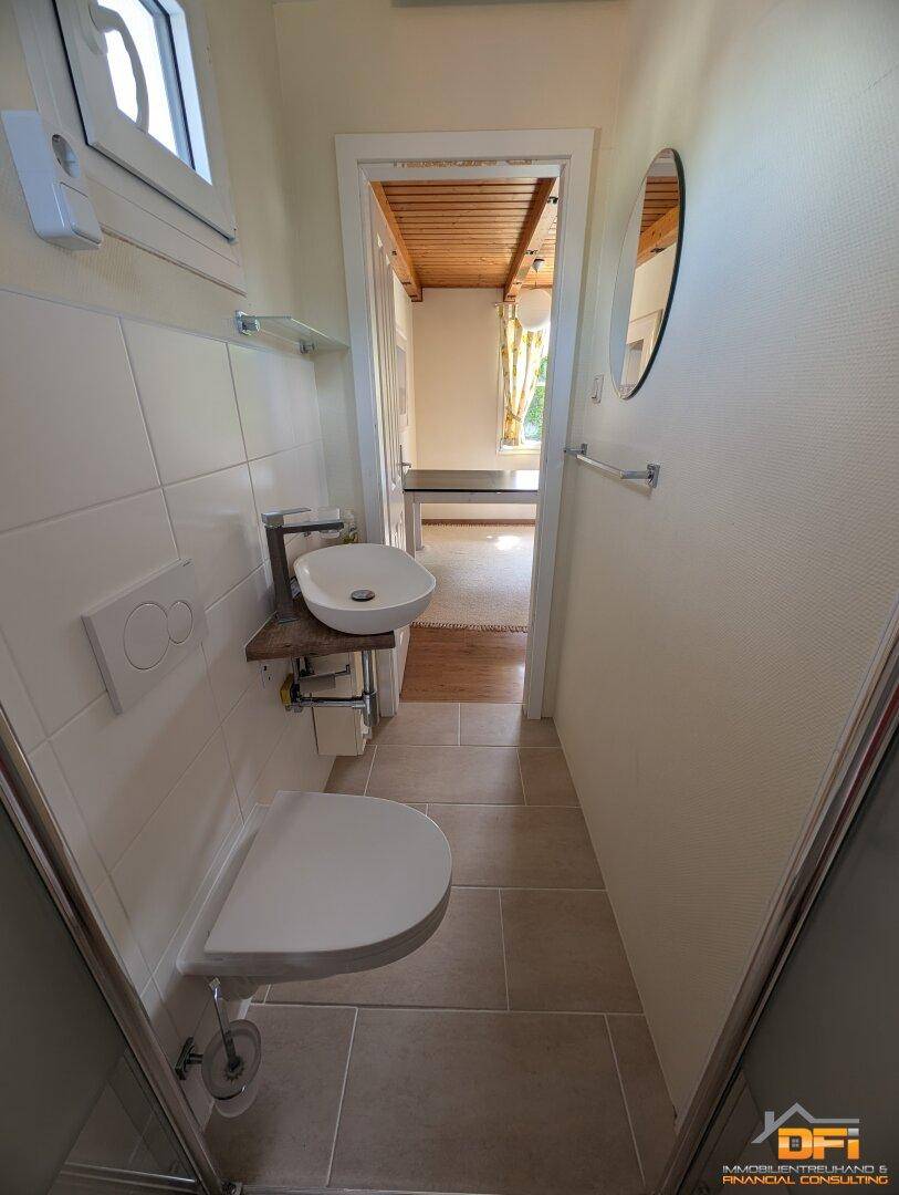 Schickes Badezimmer mit Dusche, WC und modernem Waschbecken.