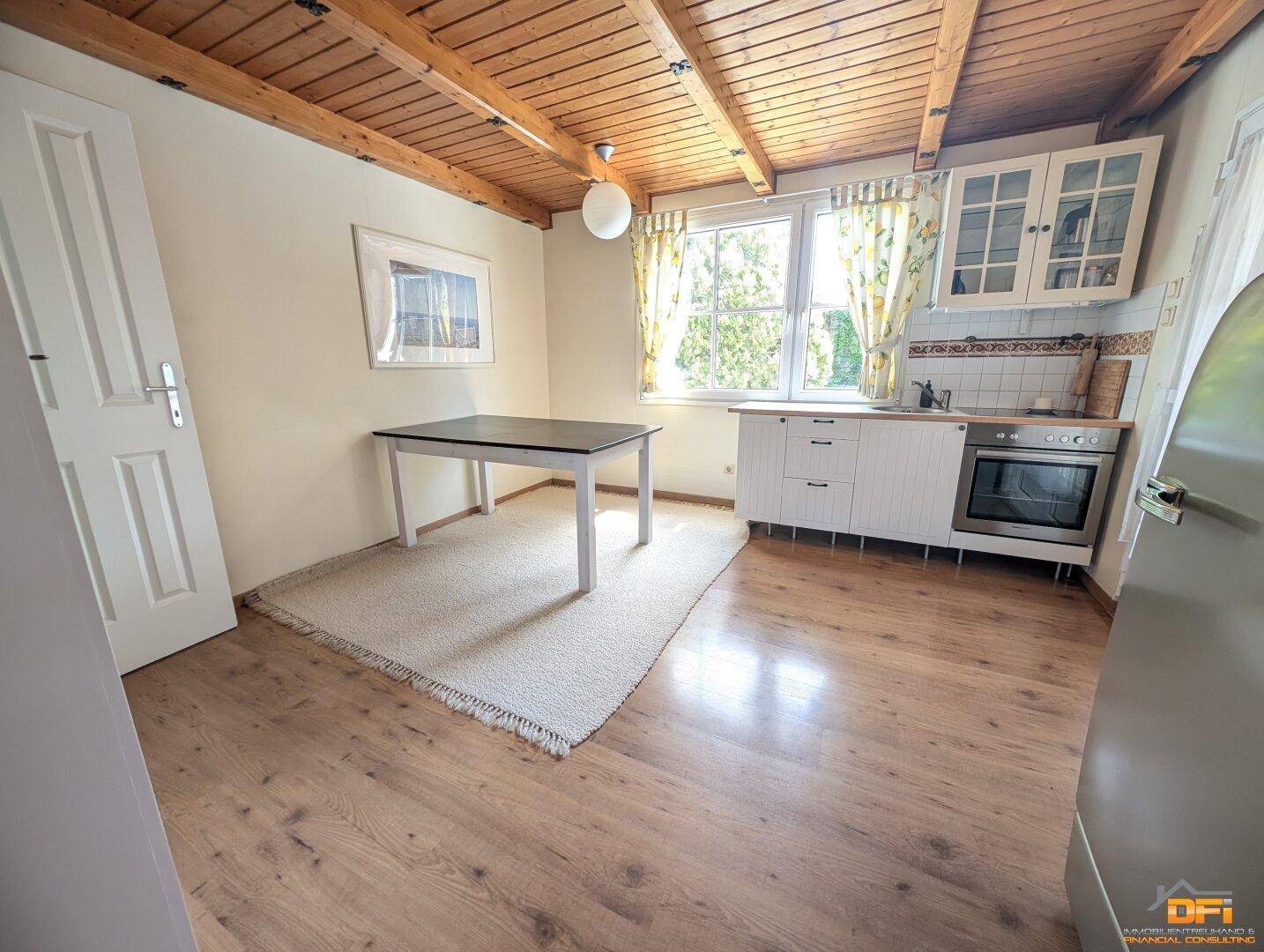 Helle Küche mit Essbereich, Fenster und Holzboden.