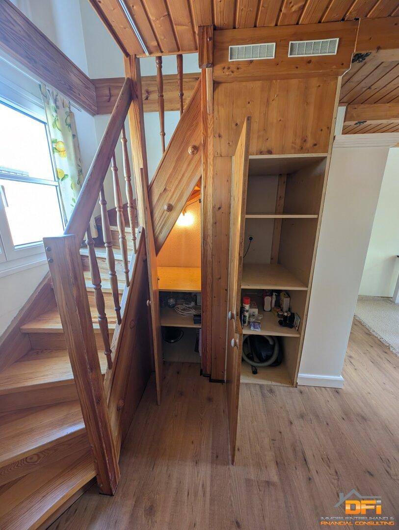 Praktischer Stauraum unter der Holztreppe mit Regalen und Schranktüren.