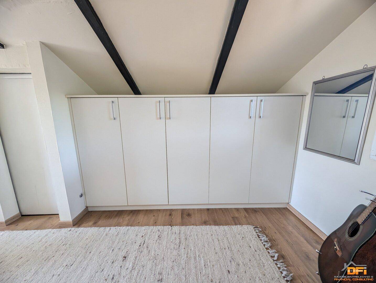 Geräumiges Schlafzimmer mit Einbauschränken, Holzboden und Dachschrägen.