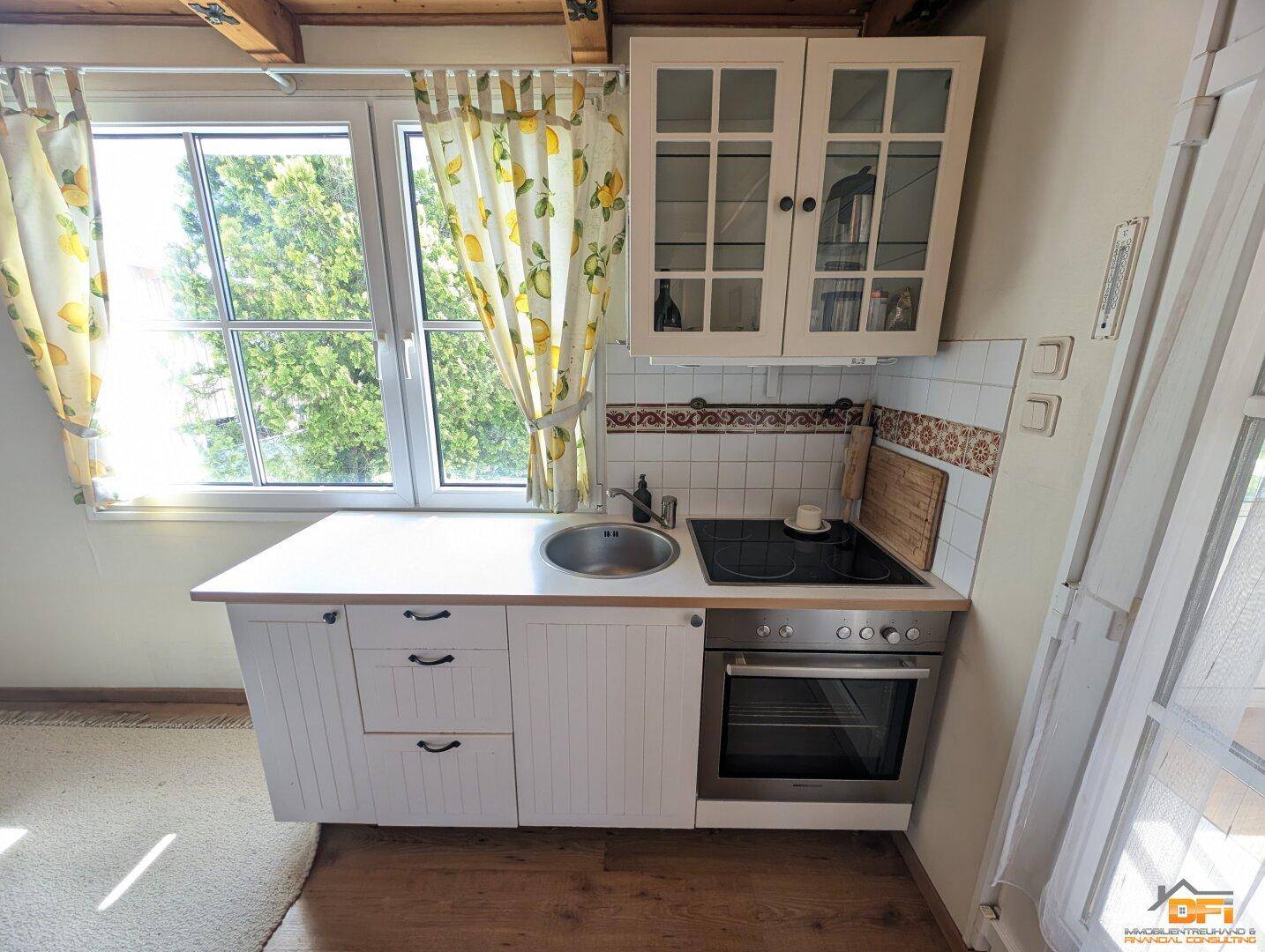 Kleine Küchenzeile mit Fenster, Herd und Backofen in hellem Design.
