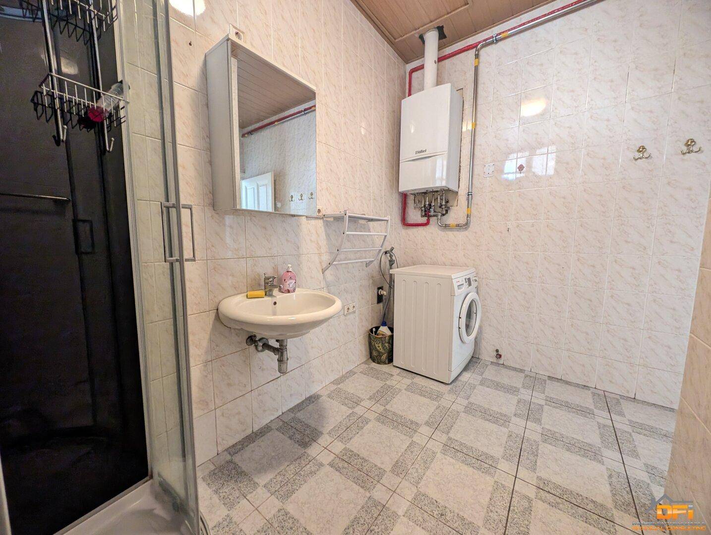 Badezimmer mit Fliesen, Duschkabine, Waschbecken und Gastherme.