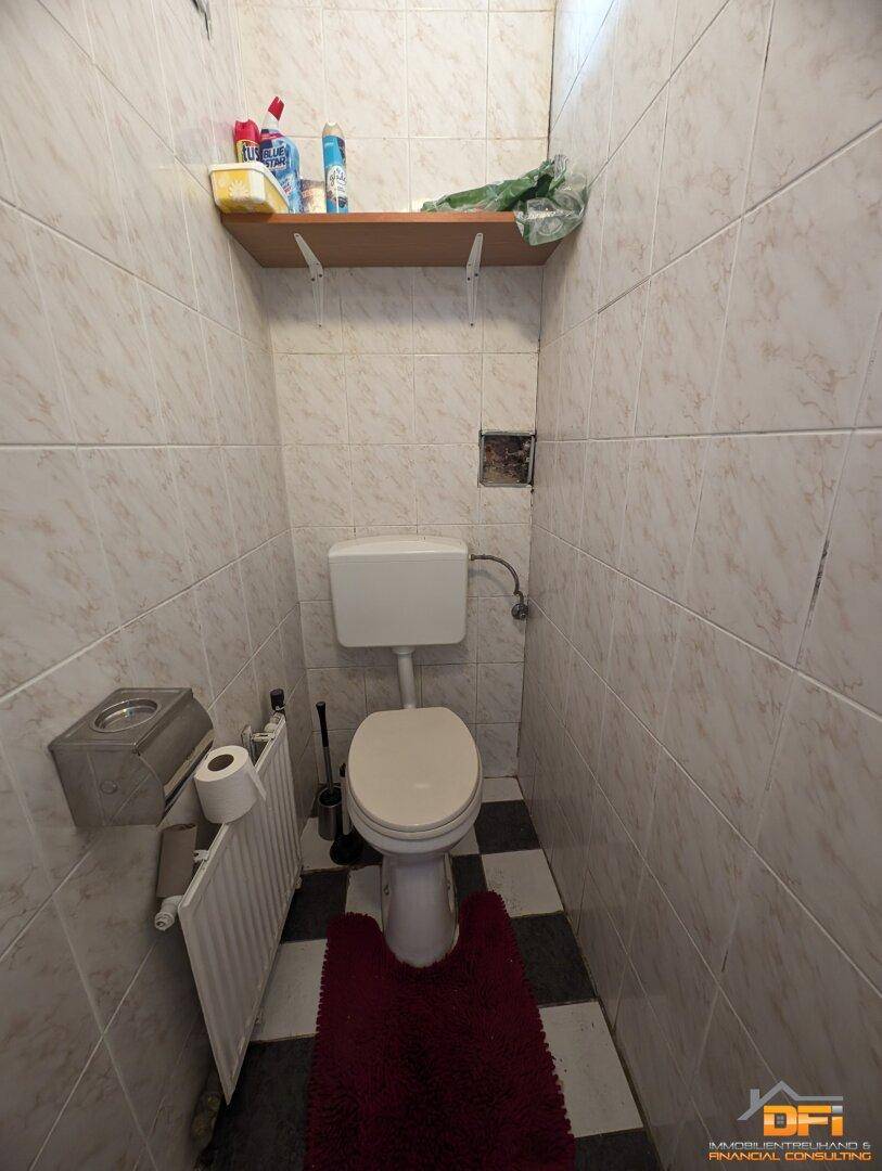 Kleines WC mit Fliesenboden und Wandfliesen.