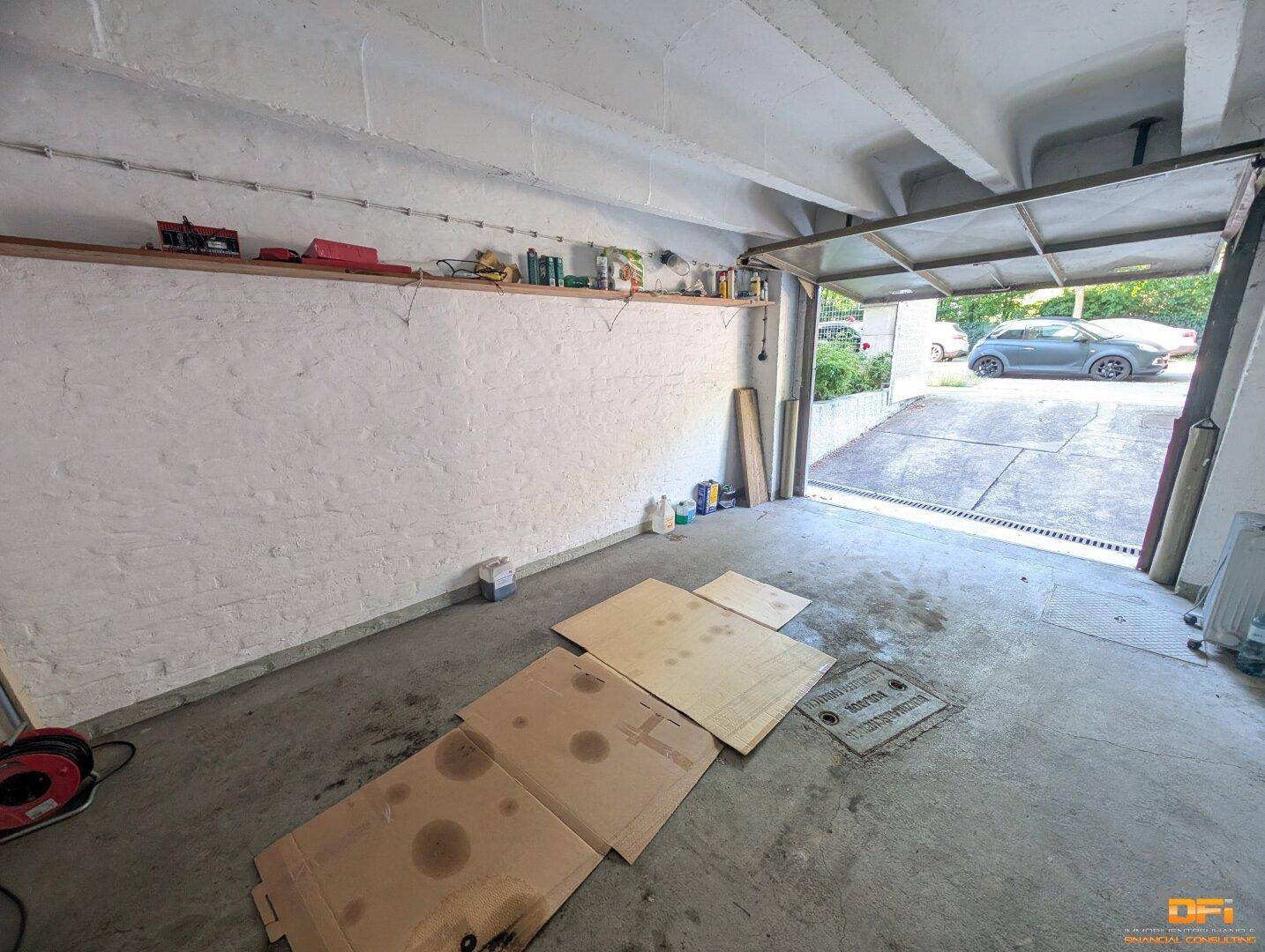 Geräumige Garage mit Regalen an der Wand und offenem Tor zur Einfahrt.