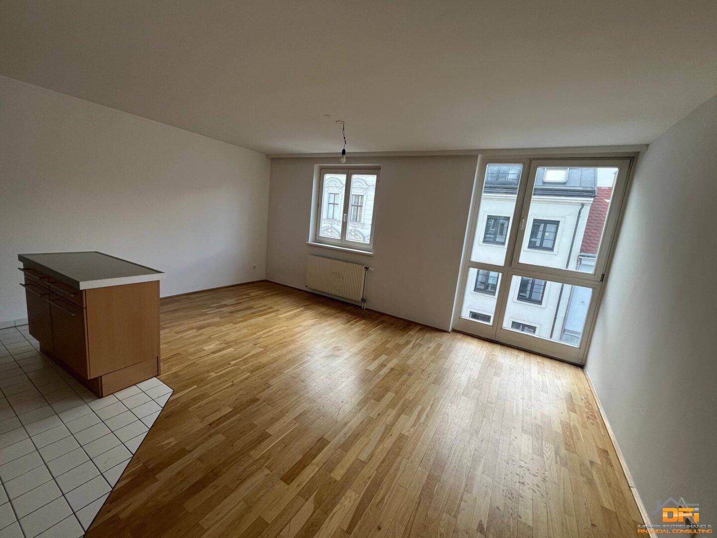 Geräumiger Wohnbereich mit großen Fenstern und Holzboden, bietet viel Tageslicht und Ausblick.