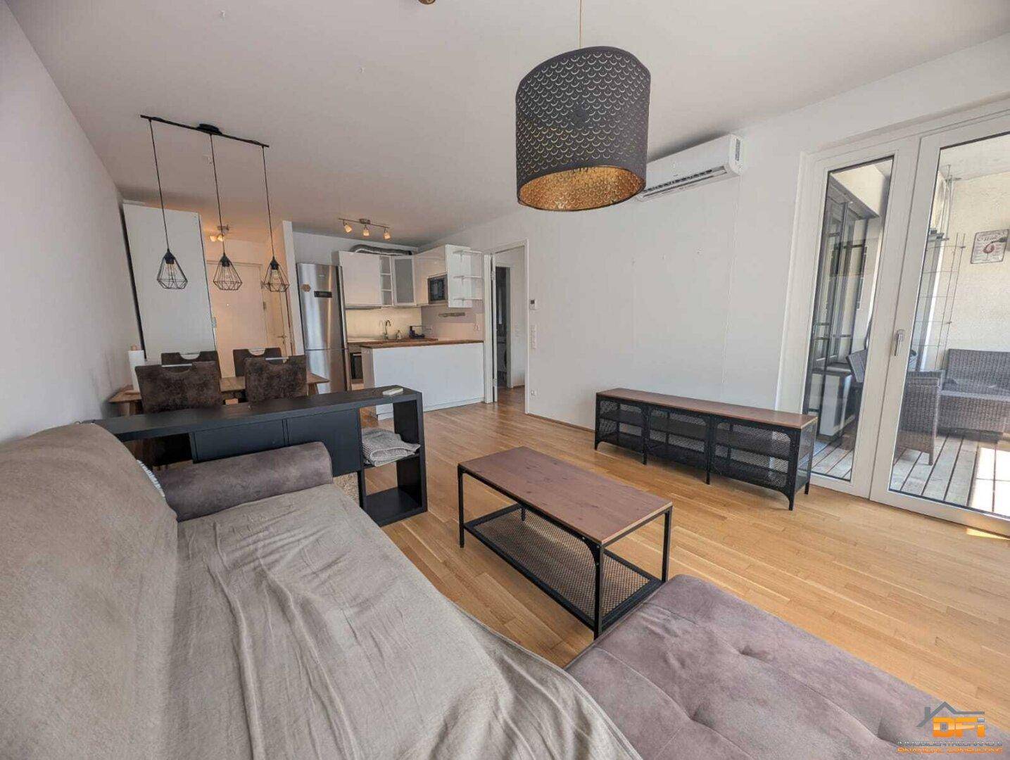 Geräumiger Wohnbereich mit Zugang zum Balkon und integrierter Küchenzeile.