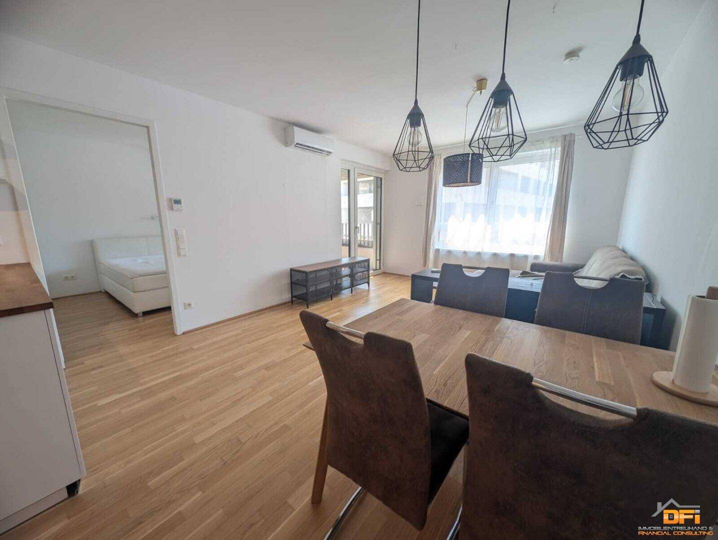 Essbereich mit Holztisch und Blick in den Wohnbereich sowie zum Schlafzimmer.