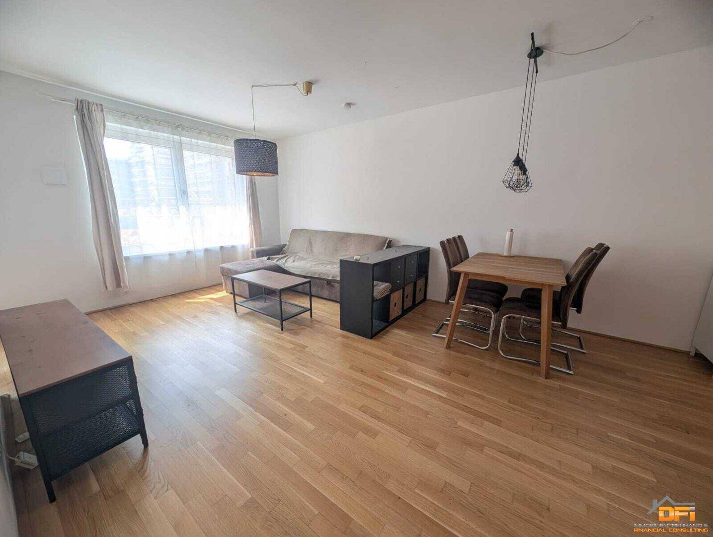 Heller Wohn- und Essbereich mit Holzboden und großem Fenster für viel Tageslicht.