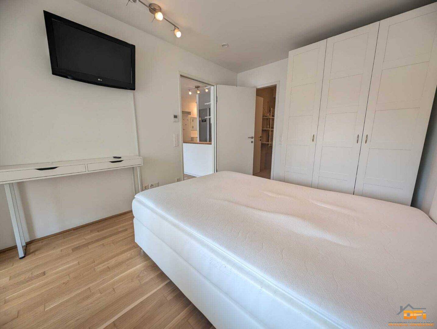 Schlafzimmer mit Doppelbett, weißem Kleiderschrank und Holzboden.