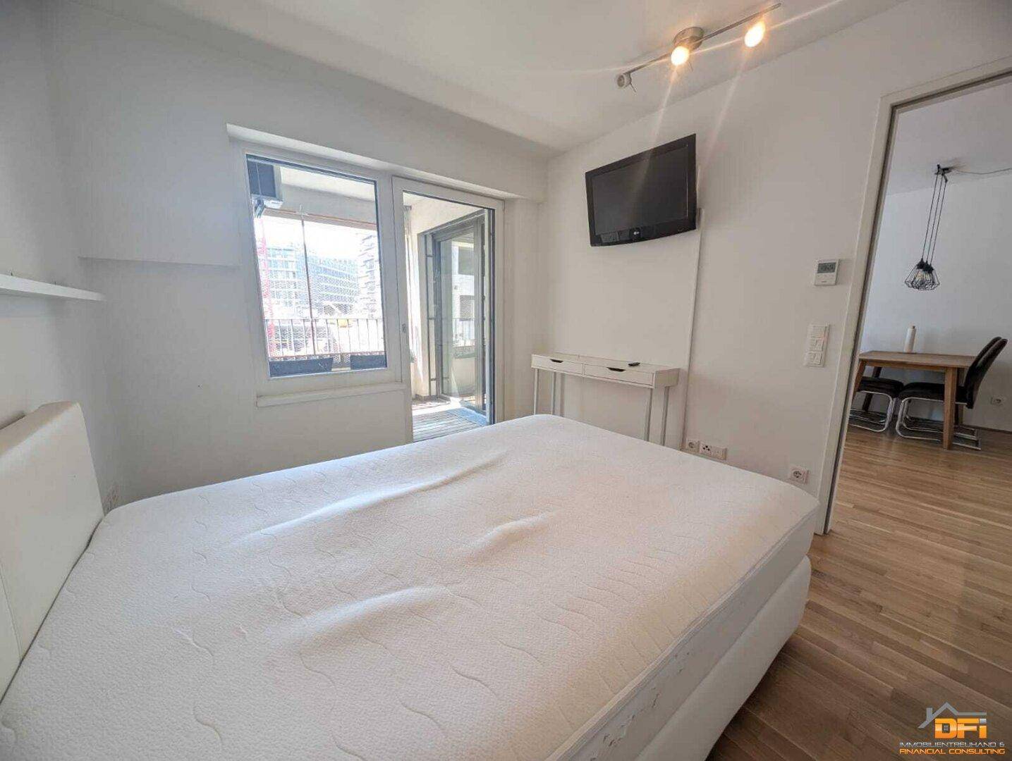 Schlafzimmer mit Balkonzugang, Doppelbett und Blick auf die Stadt.