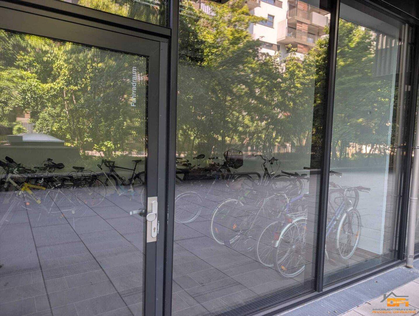 Fahrradraum mit vielen Fahrrädern, sichtbar durch eine Glasfassade.