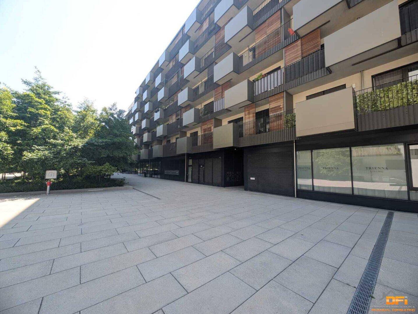 Moderne Wohnanlage mit Balkonen und gepflastertem Vorplatz.