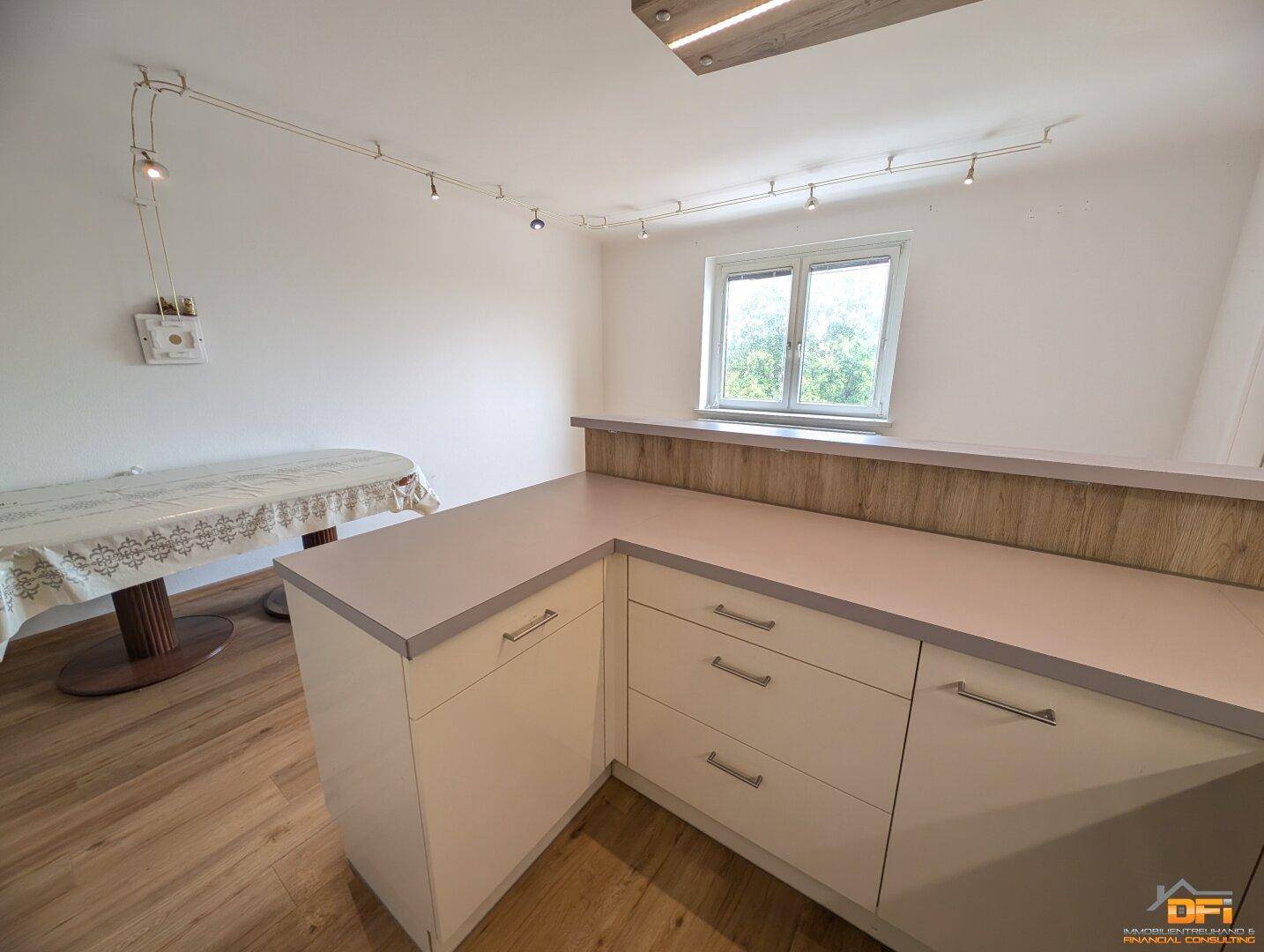 Heller Essbereich mit Laminatboden, großem Fenster und direkter Anbindung zur Küche.