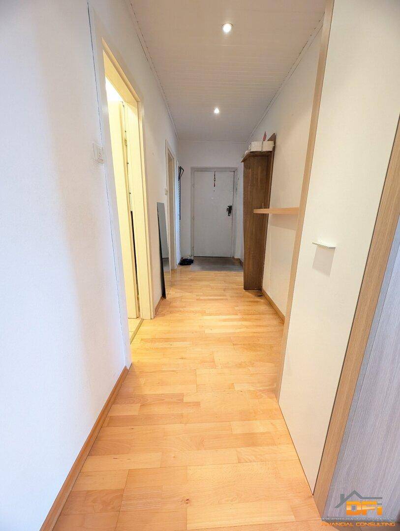 Heller Flur mit Holzparkettboden und Zugang zu verschiedenen Zimmern.