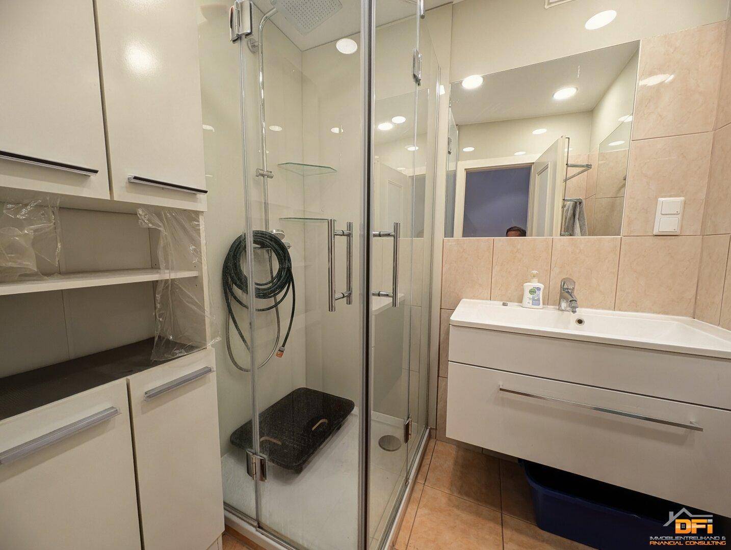 Modernes Badezimmer mit Duschkabine, Waschtisch und hellen Fliesen.