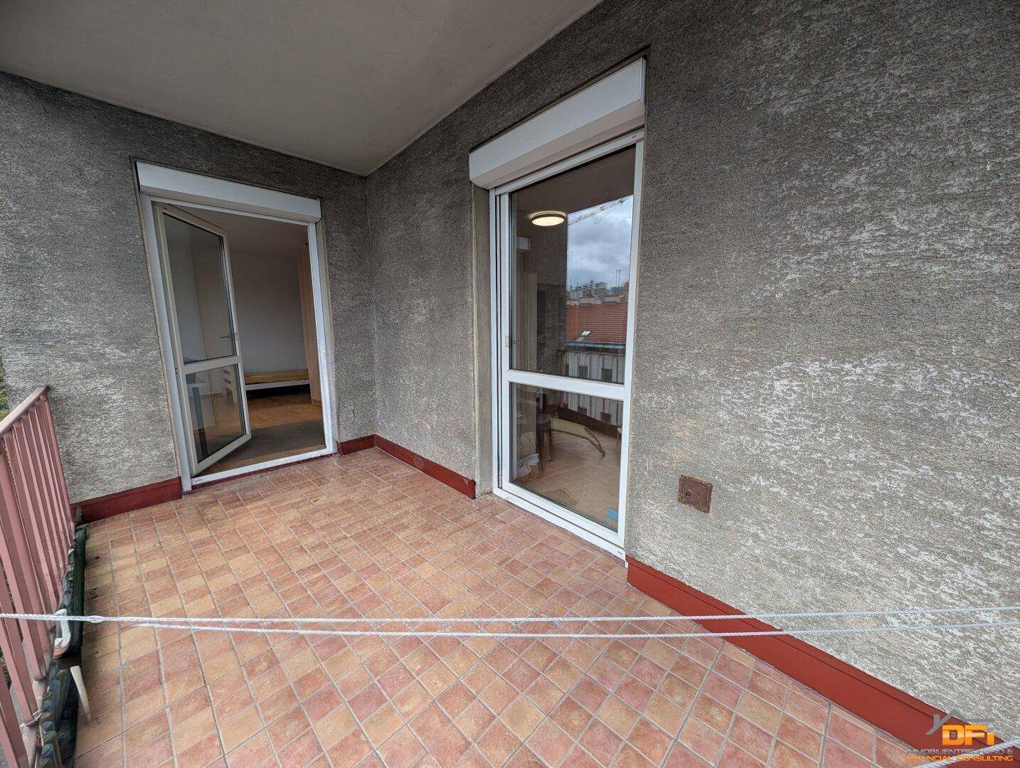 Überdachter Balkon mit Fliesenboden und Zugang zu den Innenräumen.