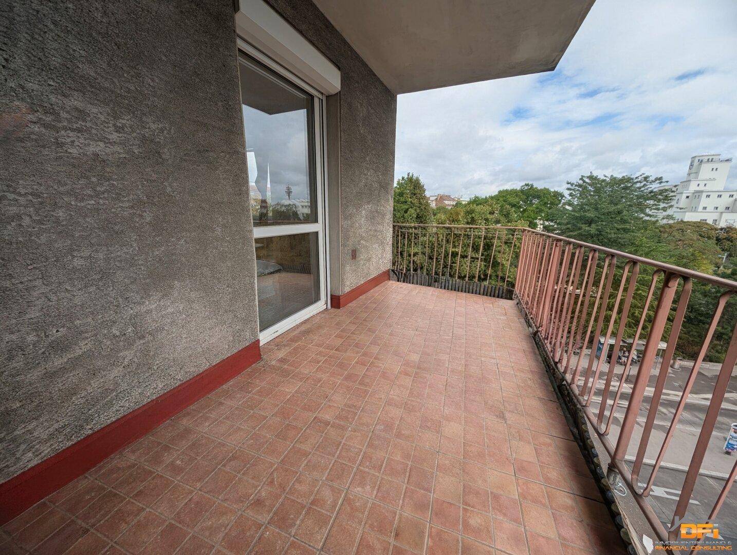 Geräumiger Balkon mit Fliesenboden, Metallgeländer und Blick auf die Umgebung.