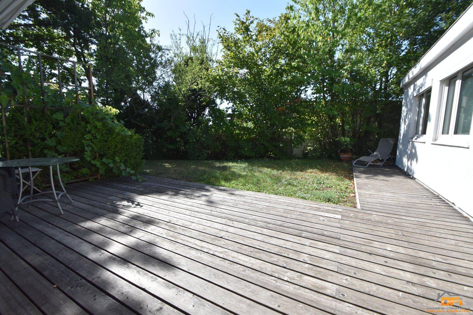 Geräumige Holzterrasse mit Sitzgelegenheiten und Blick in den grünen Garten.