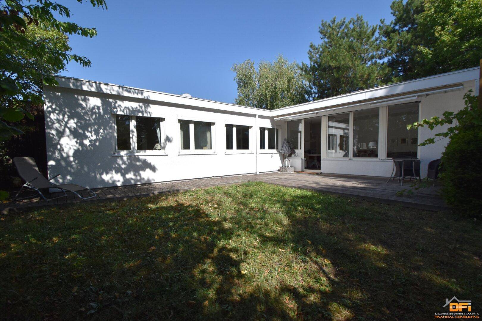 Außenansicht des Hauses mit großer Holzterrasse und weitläufigem Gartenbereich.