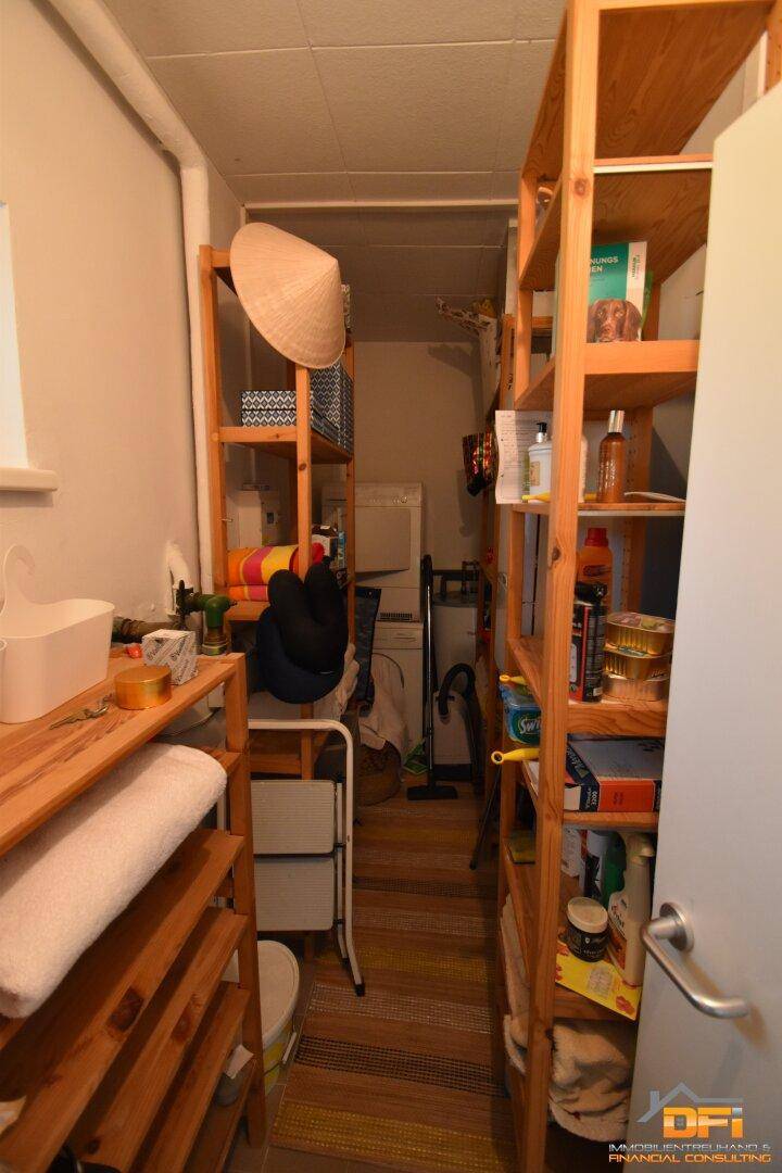 Praktischer Abstellraum mit Holzregalen und Platz für eine Waschmaschine.