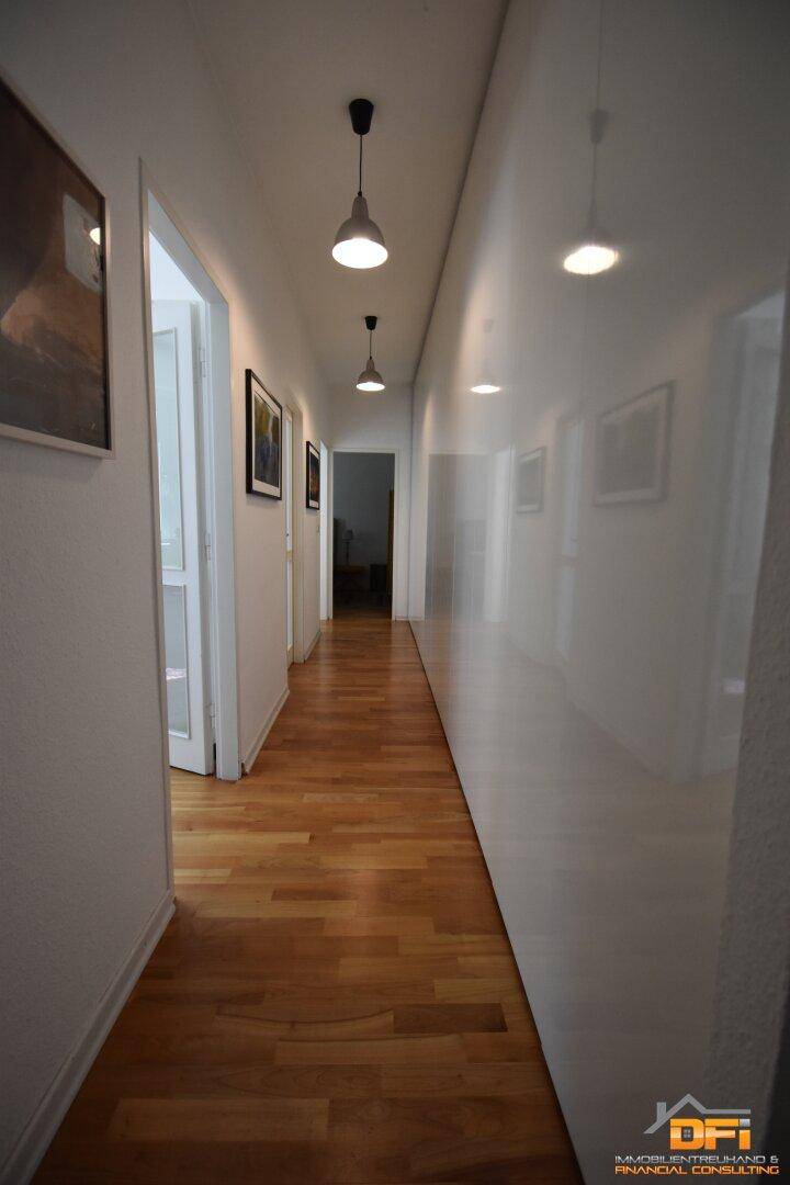 Langer Flur mit Holzboden und modernen Deckenleuchten.