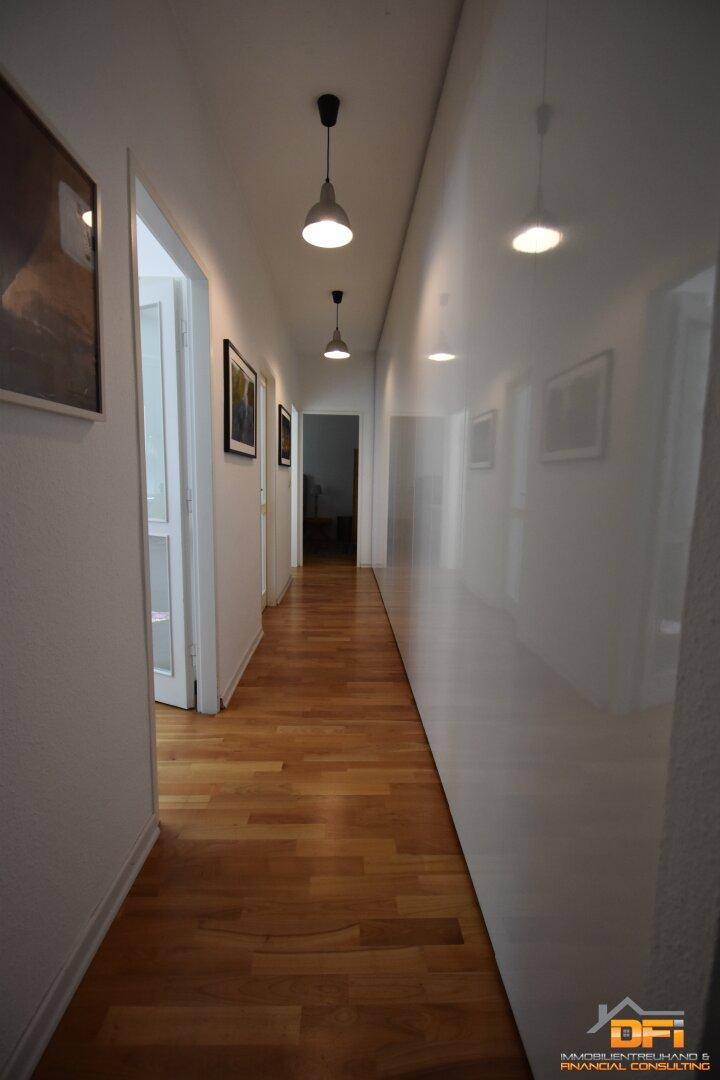 Langer Flur mit Holzboden und modernen Deckenleuchten.