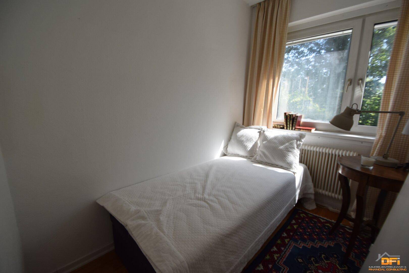 Kleines Schlafzimmer mit Einzelbett, Holzboden und Fenster zum Garten.