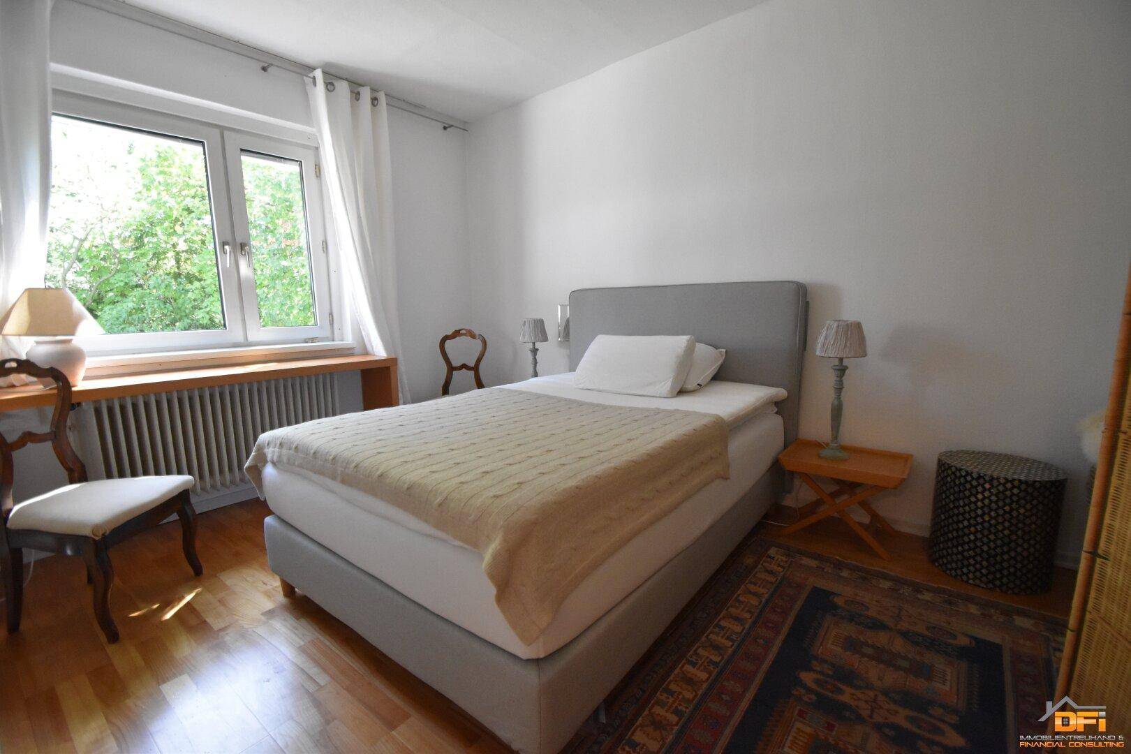 Gemütliches Schlafzimmer mit Doppelbett, Holzboden und Blick ins Grüne.