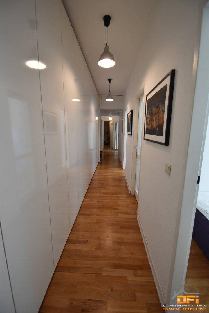 Heller Flur mit Holzboden, Einbauschränken und modernen Leuchten.