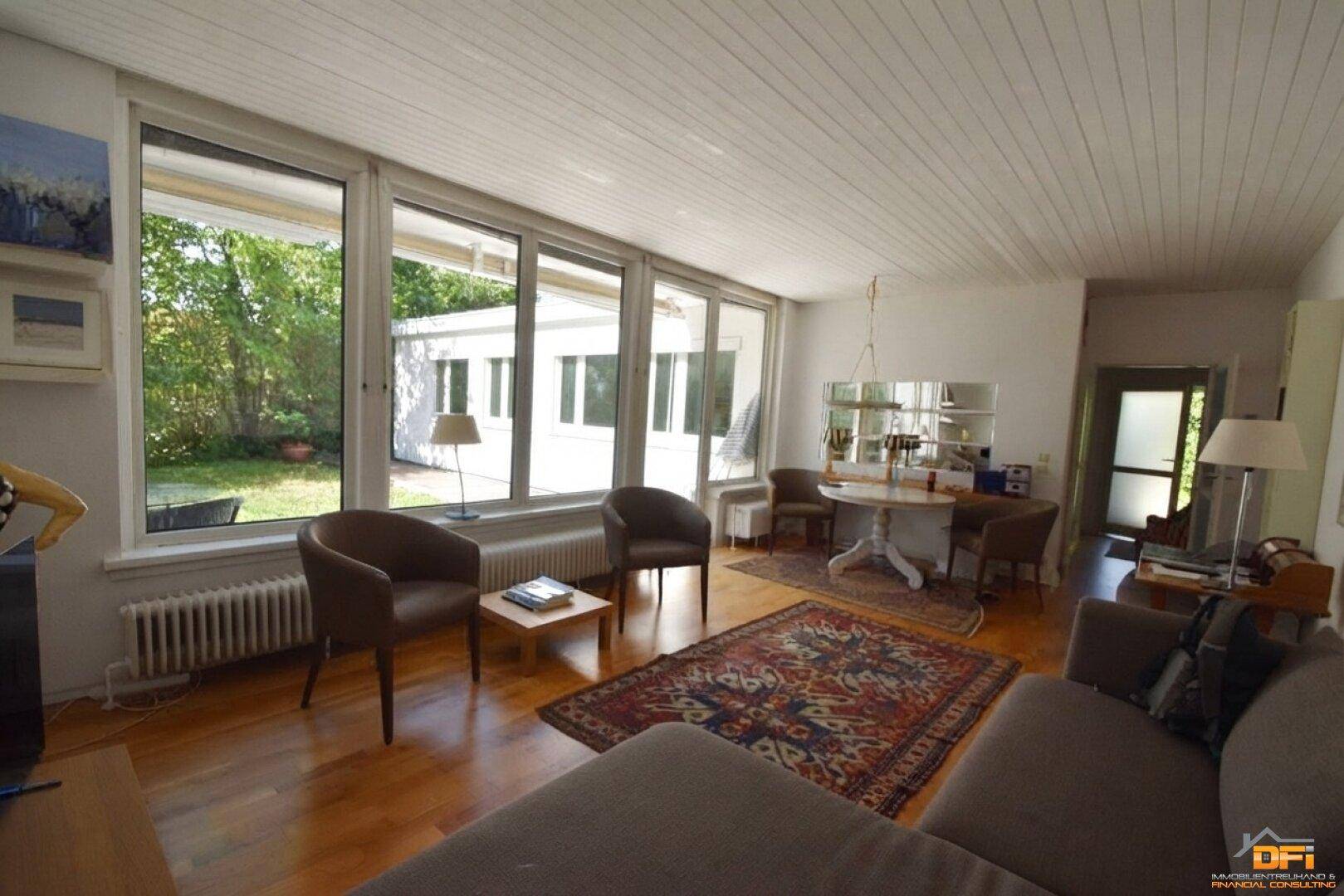 Geräumiger Wohn- und Essbereich mit großen Fenstern und Blick in den Garten.