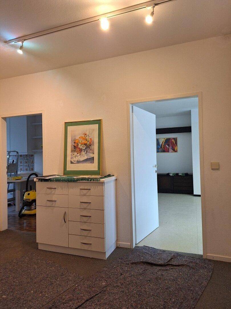 Flur mit weißer Kommode und Bildern, der zu verschiedenen Räumen führt, mit Teppichboden.