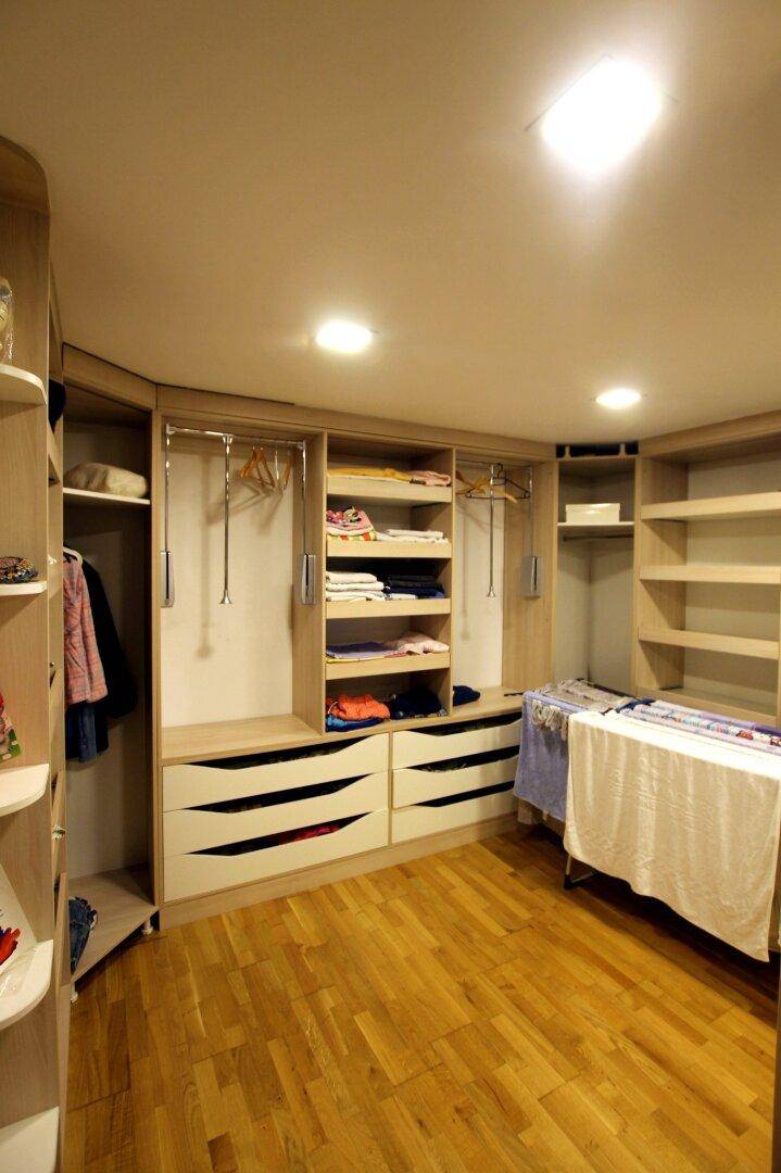 Geräumiger begehbarer Kleiderschrank mit Holzregalen und viel Stauraum für Kleidung.