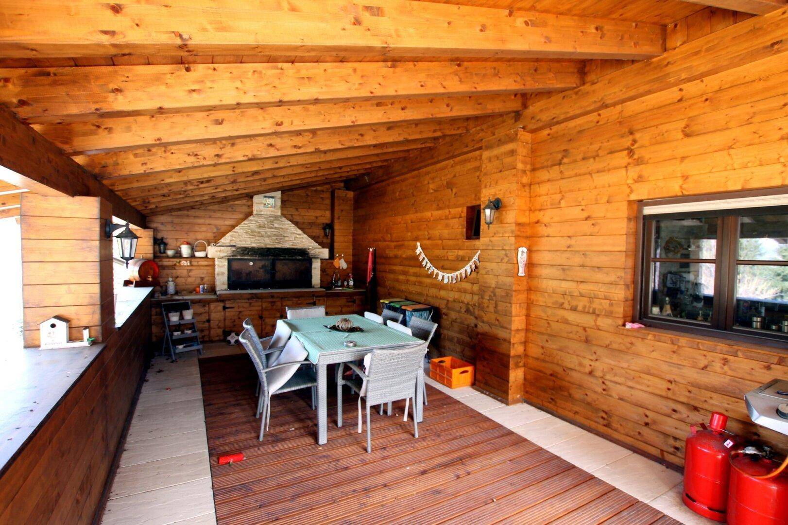 Große überdachte Holzterrasse mit Essbereich, Grill und Außenkamin für gesellige Abende.