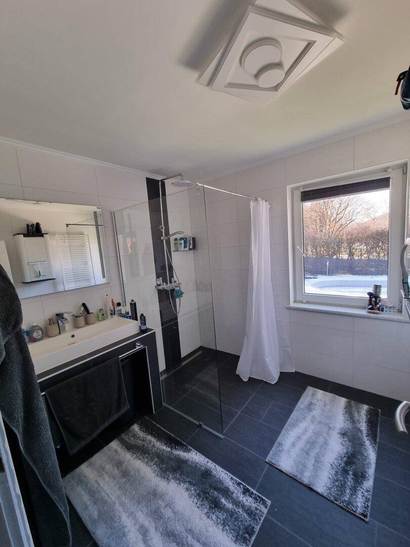 Modernes Badezimmer mit großer ebenerdiger Dusche, Einzelwaschbecken und Fenster.