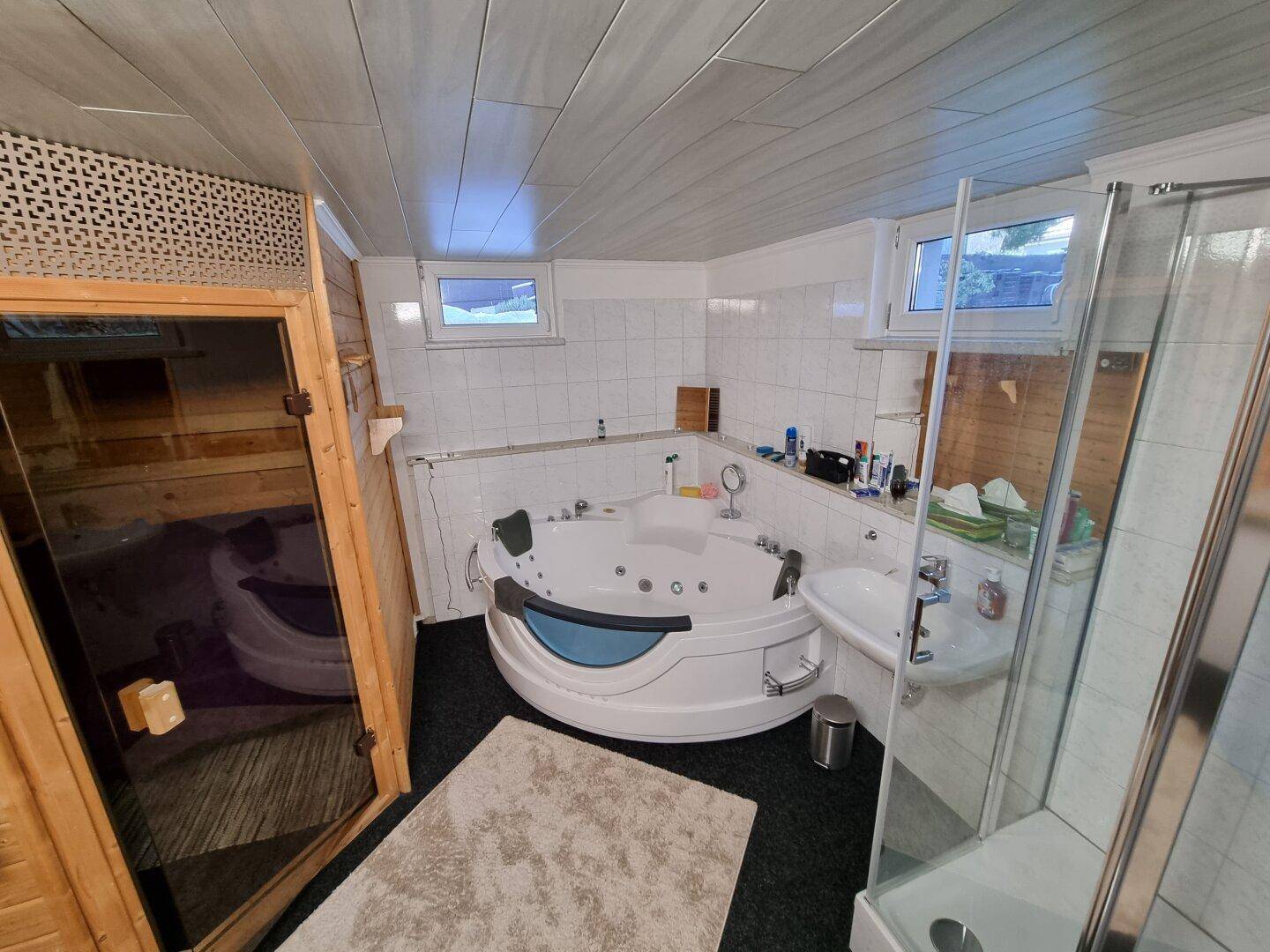 Großzügiges Badezimmer mit Whirlpool, integrierter Sauna und separater Dusche.