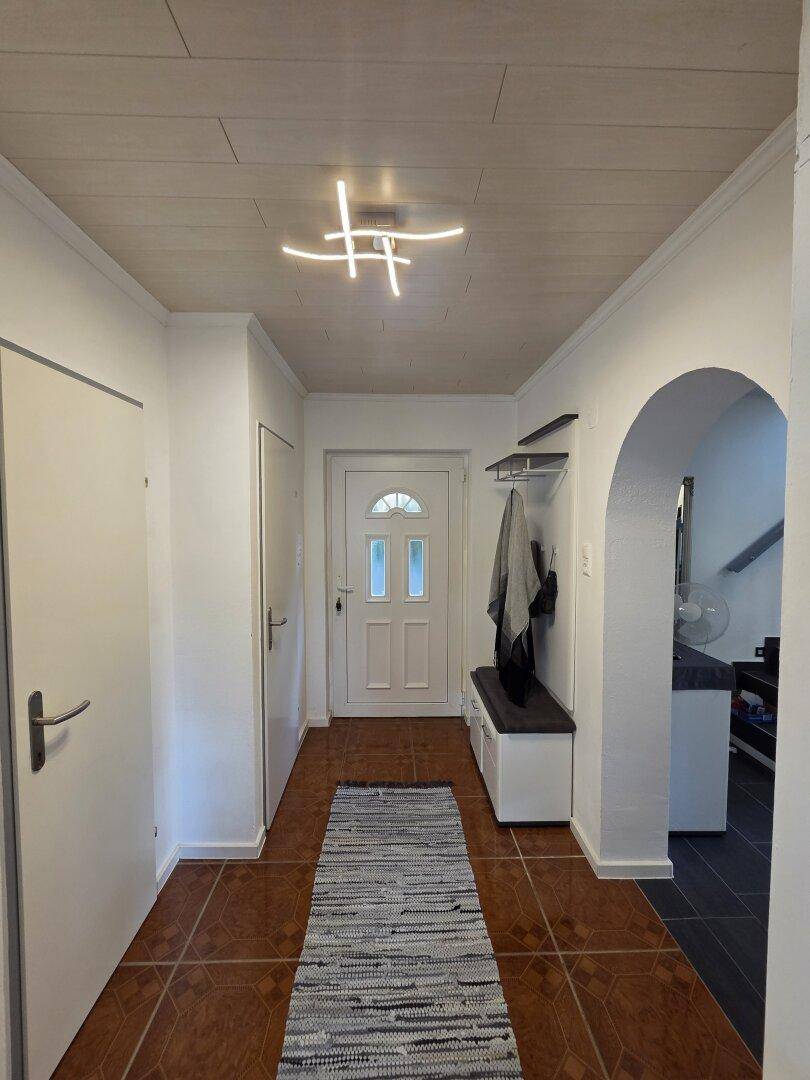 Freundlicher Eingangsbereich mit Garderobe, Fliesenboden und Zugang zu weiteren Räumen.