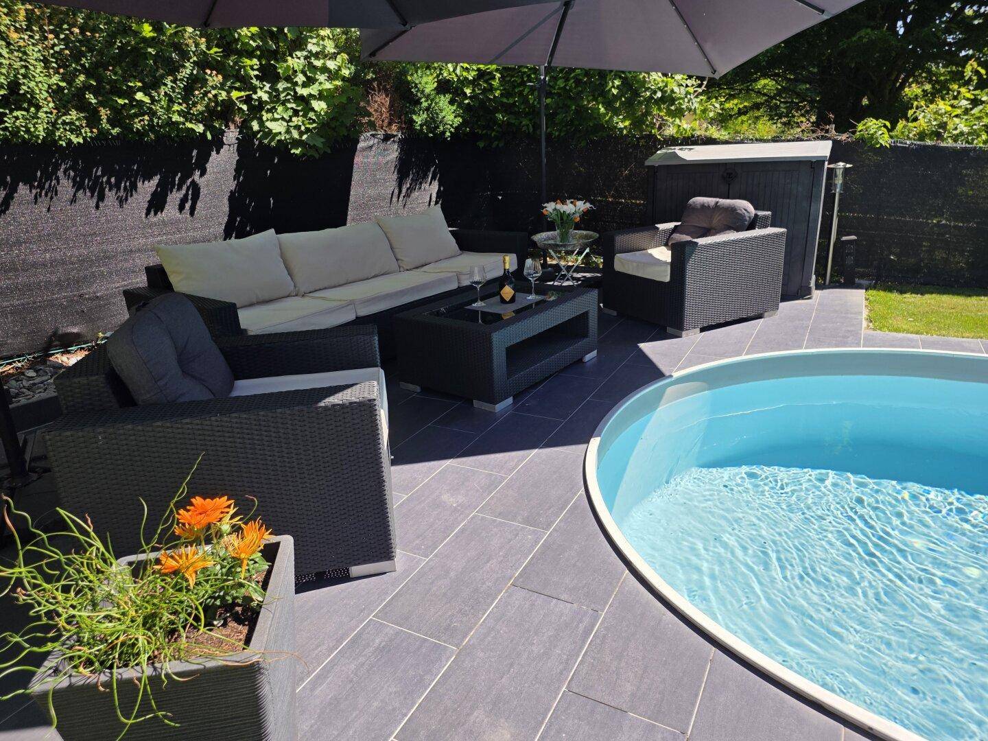Gemütliche Terrasse mit Lounge-Möbeln, Sonnenschirm und kleinem Pool für entspannte Stunden.