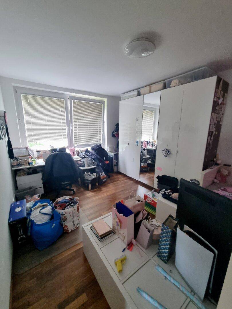 Kinderzimmer oder Arbeitszimmer mit Holzboden, Schreibtisch und Spiegelschrank.