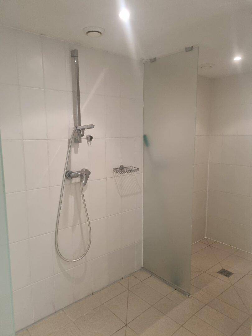 Duschbereich in der Wellnessanlage mit hellen Fliesen und Glasabtrennung.