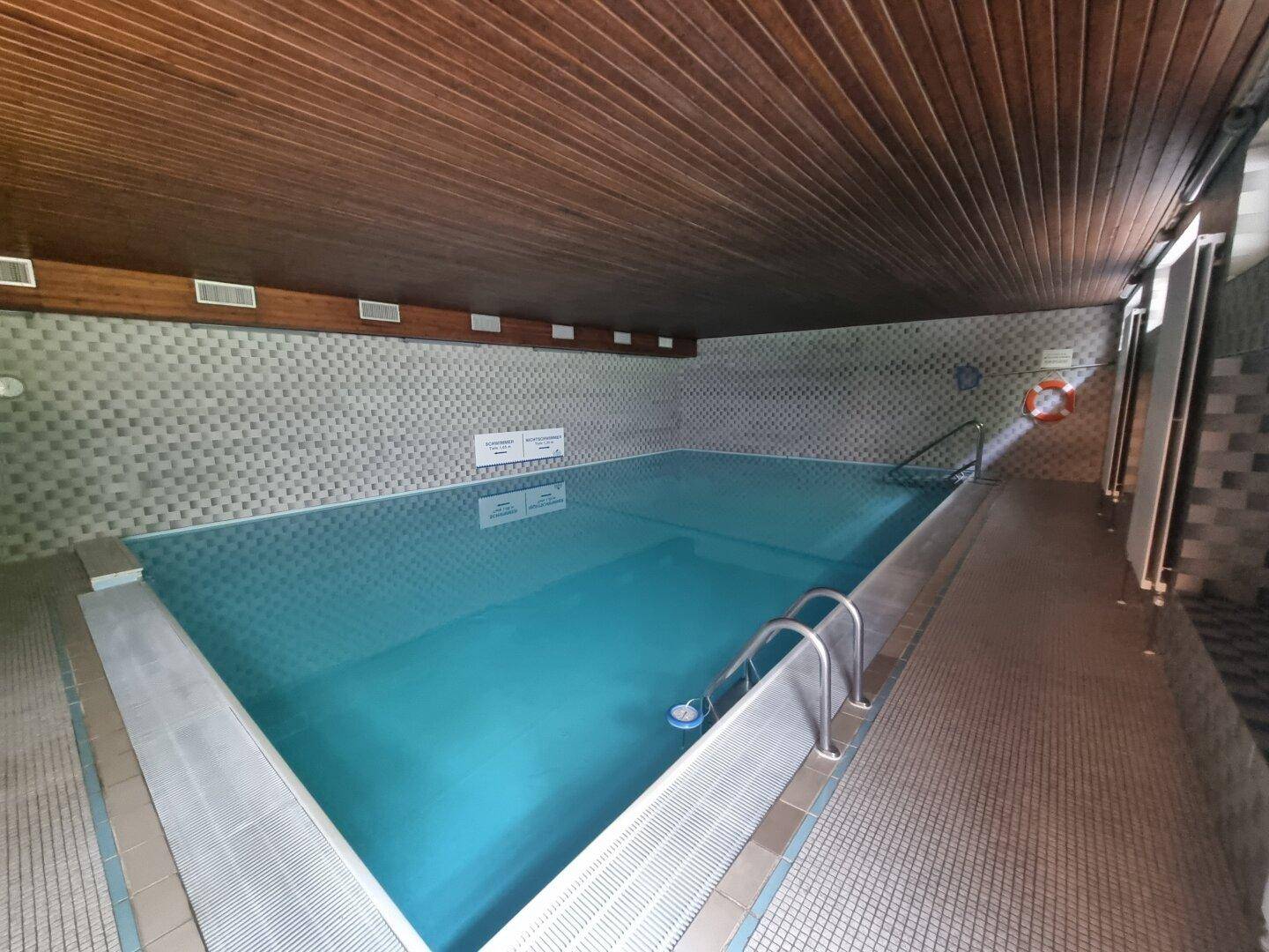 Innenpoolbereich mit Holzdecke und blauen Fliesen, ideal für Entspannung und Sport.