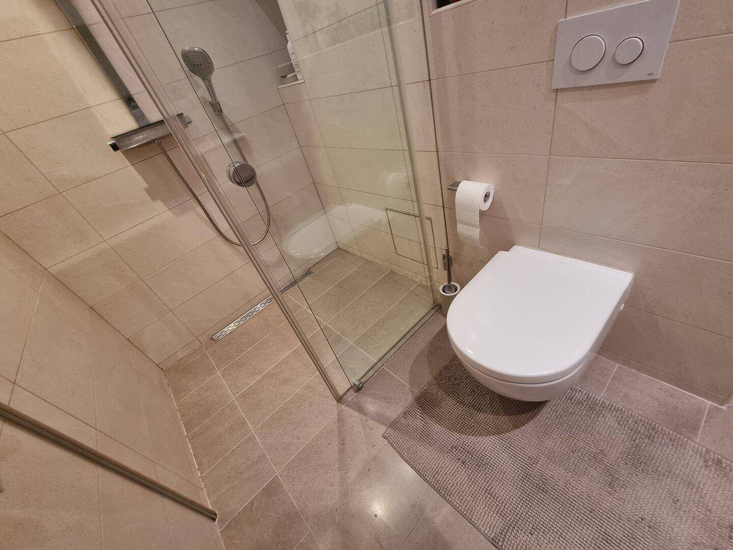 Modernes Badezimmer mit ebenerdiger Dusche und wandhängendem WC.